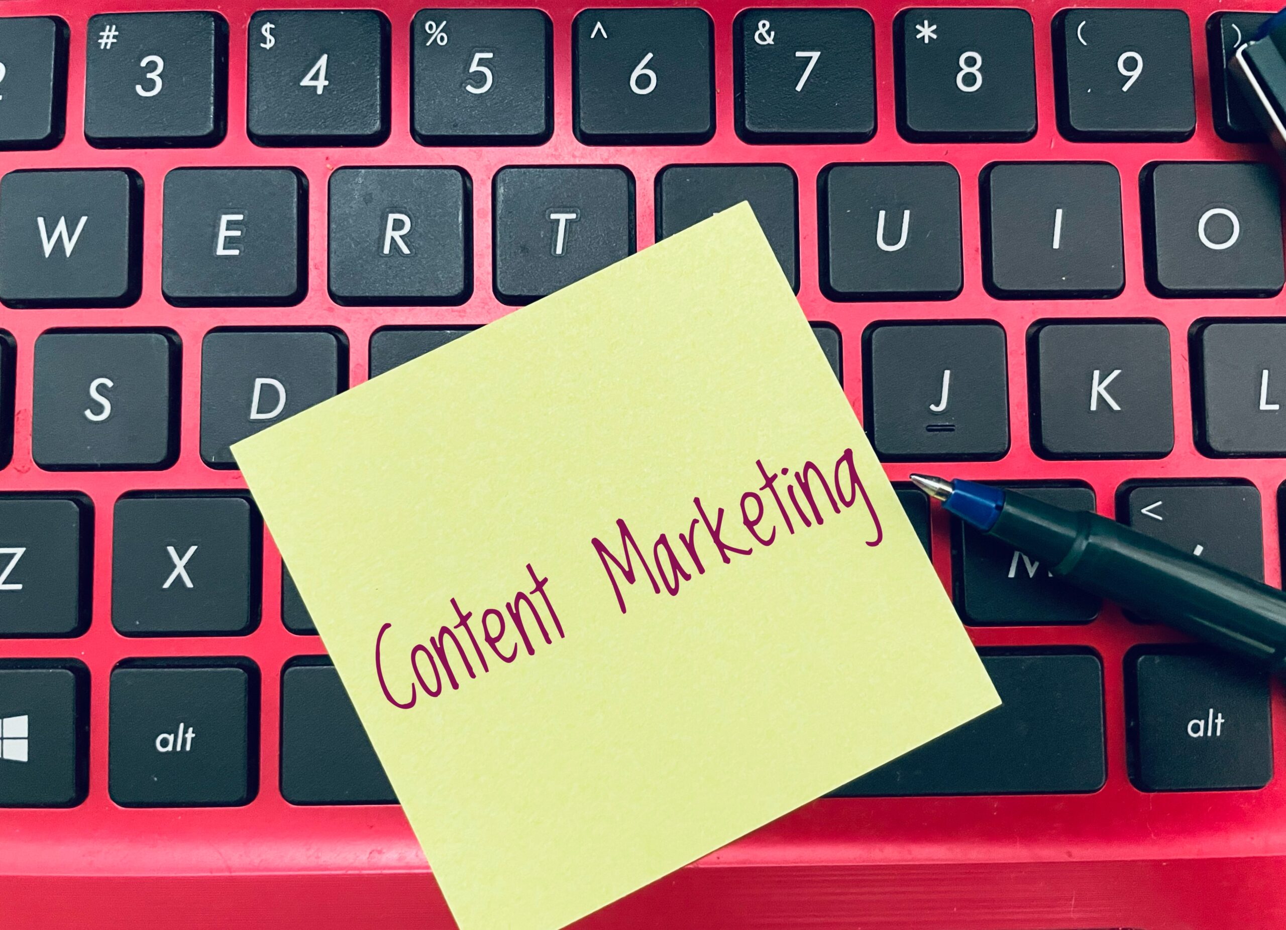 Laptop of digital marketer with a posit note on the keyboard that reads "content marketing".