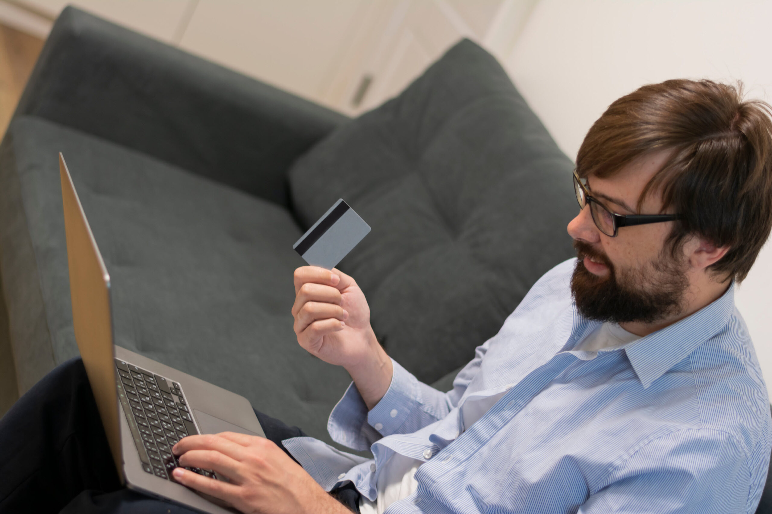 Image of a man with a laptop, holding a credit card.